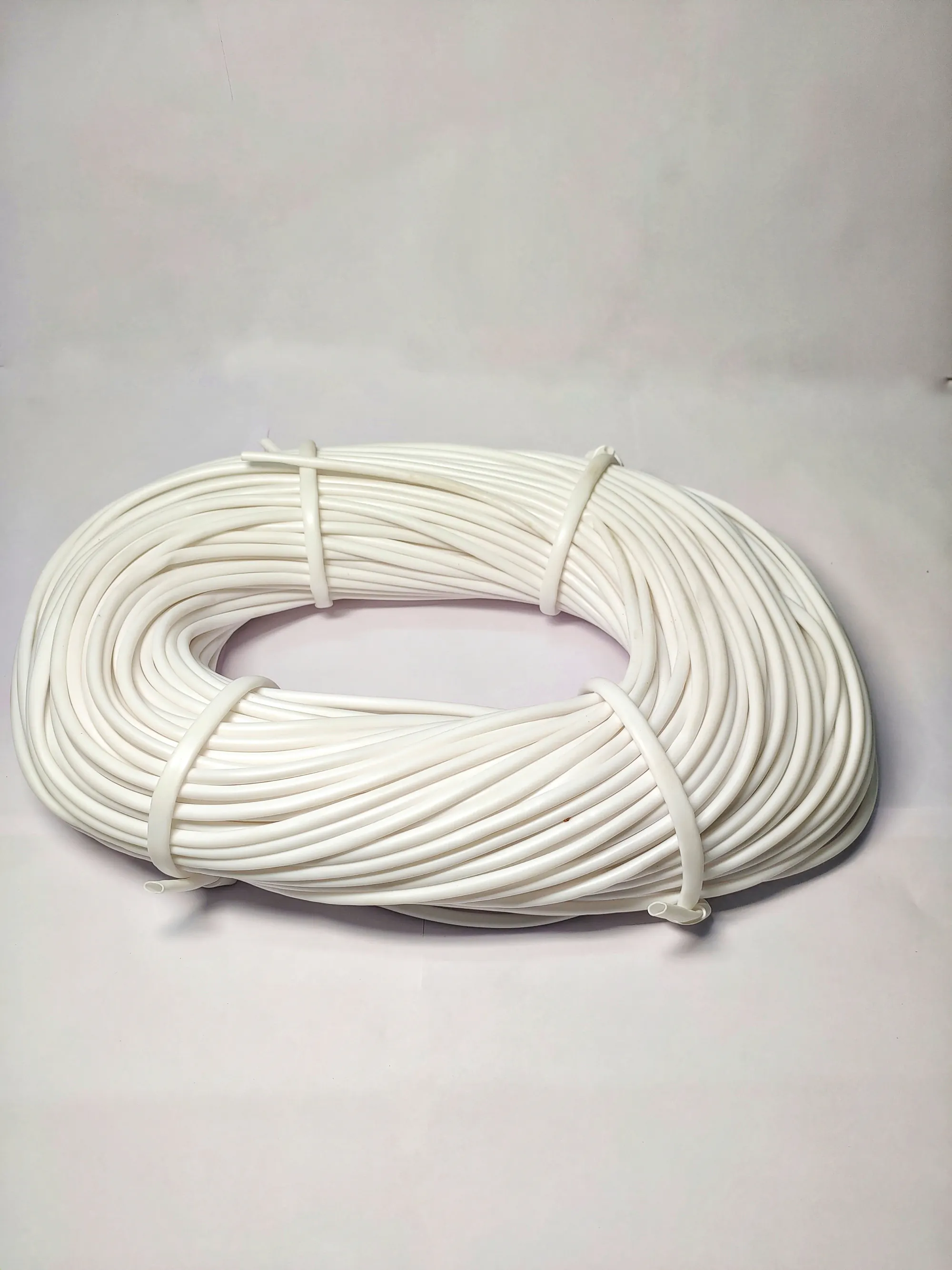 Coil of white printable PVC tubing tied in four places